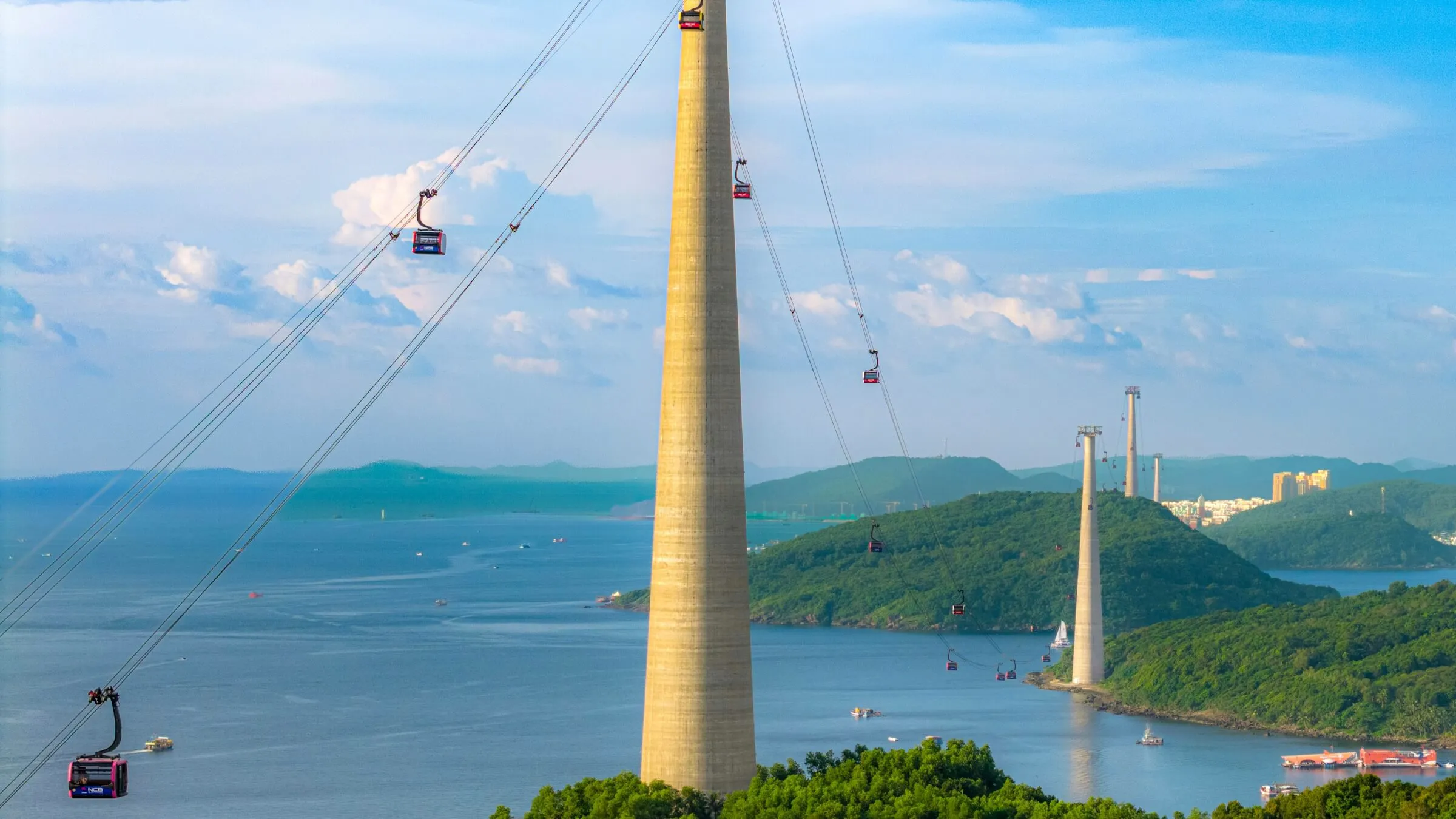 Phu Quoc Cable Car cabins on cables strung between tall concrete towers over the sea and green islets of the An Thoi archipelago